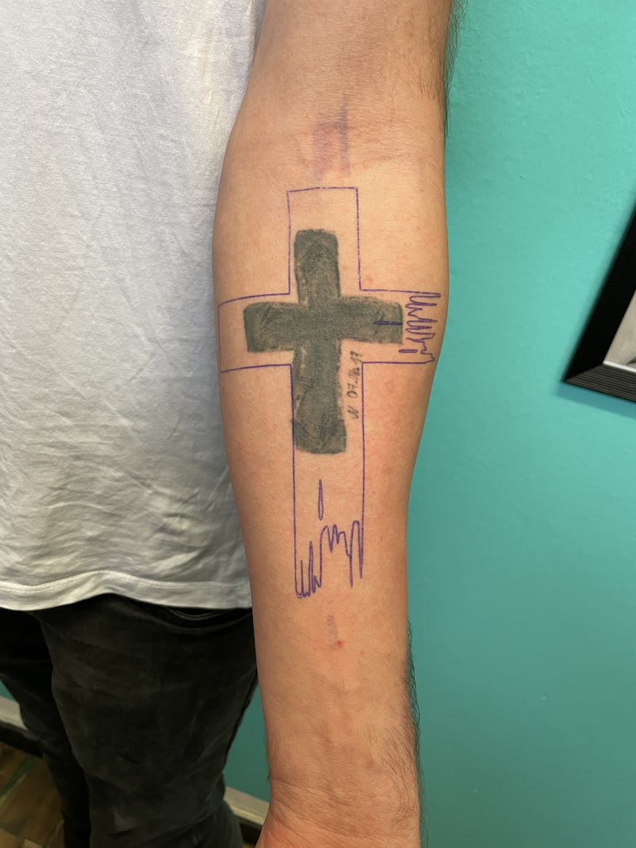 Bestehendes Kreuz-Tattoo mit eingezeichneter neuer Form am Unterarm