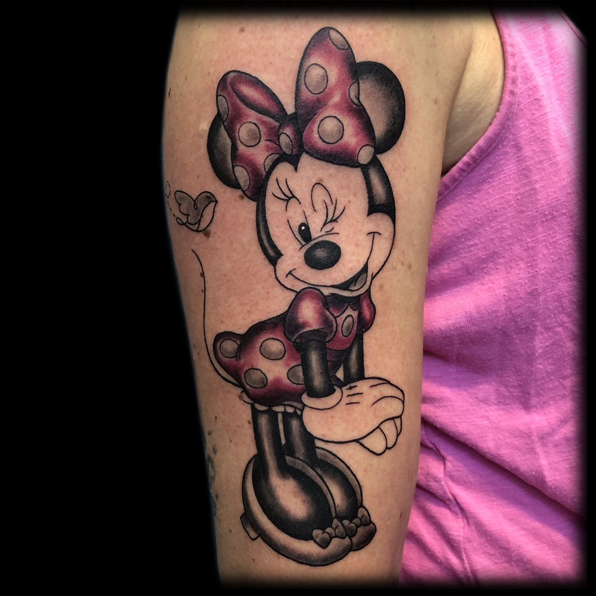 Farbiges Comic-Tattoo einer Maus mit Schleife auf einem Oberarm