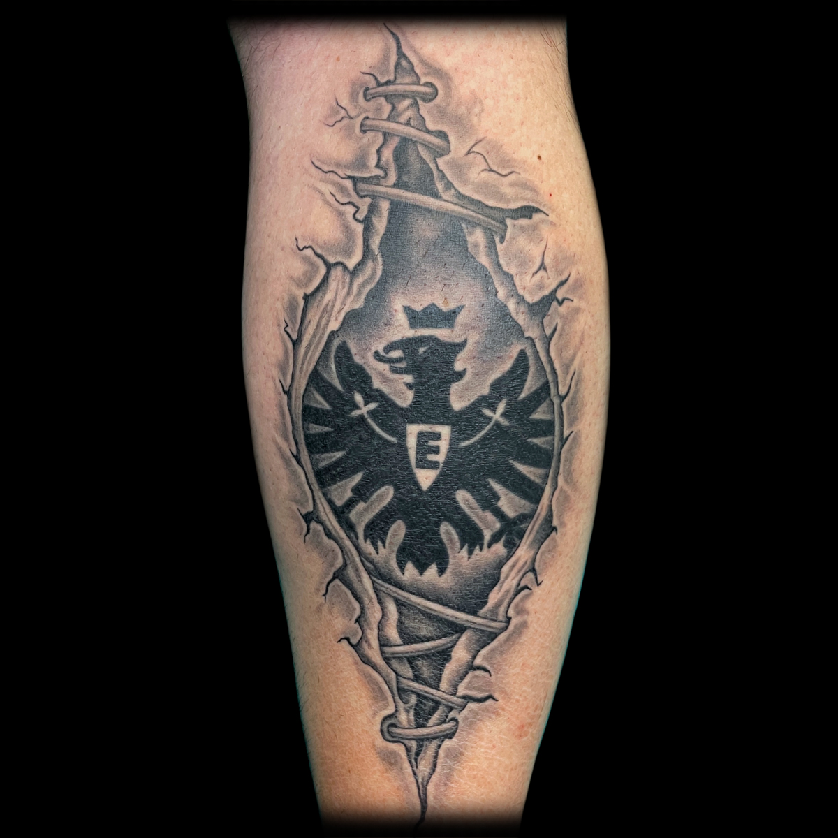 Schwarz-graues Adler- und Stadionmotiv auf einem Unterschenkel