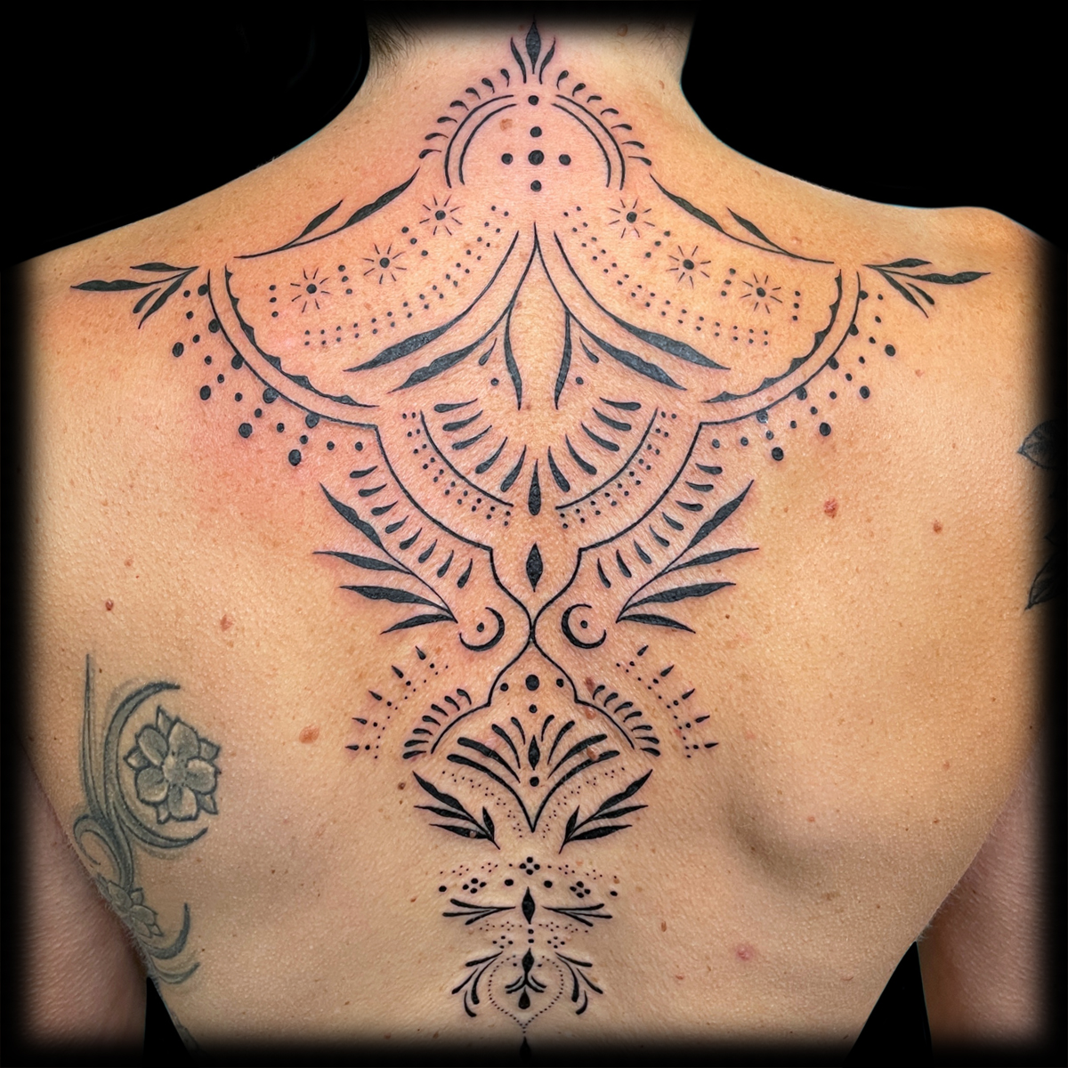 Symmetrisches ornamentales Tattoo über dem oberen Rücken